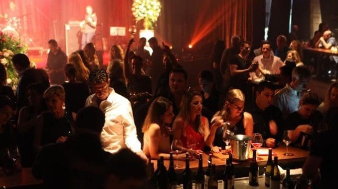 מסביב לרחבה המרכזית ישבו האורחים, חלקם סביב שולחנות ואחרים ליד דלפק ארוך