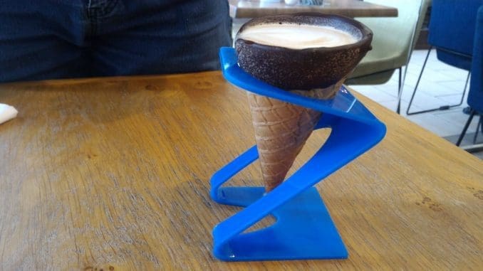 לשתות  קפוצ'ינו מתוך גביע גלידה מעוטר בשוקולד